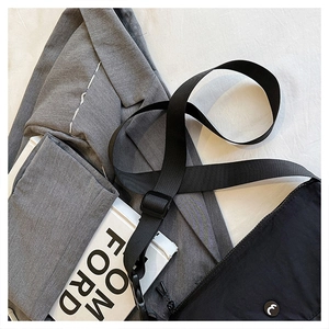 Detail of black nylon saddle bag with 'e' emblem near a grey blazer and book