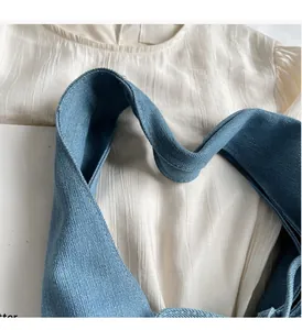 Close-up of durable blue denim tote bag handles and reinforced stitching detail