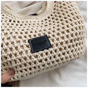 Close-up of beige crochet tote bag showing woven texture and black logo patch