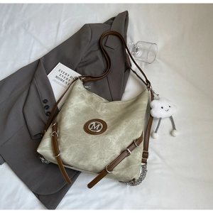 Close-up of vintage large tote bag with textured fabric, brown leather trim and M logo