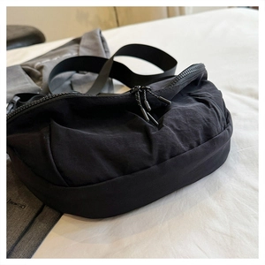 Detail of minimalist black nylon crescent bag featuring durable fabric and dual zippers