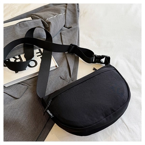 Detail of black nylon crescent crossbody bag with adjustable wide strap and side label
