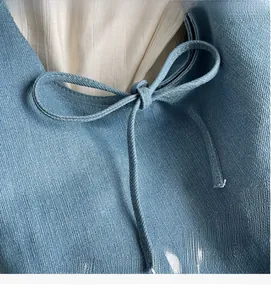 Detail of light blue denim tote with lace-up bow and white printed letters