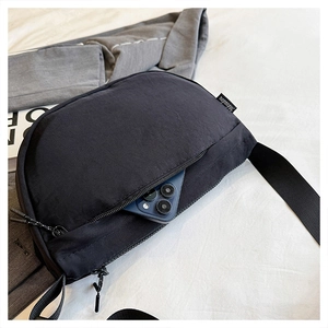 Detailed view of the front zipper pocket on a black nylon crescent bag holding a smartphone