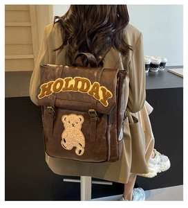 Detail of vintage brown faux leather backpack with plush bear and HOLIDAY embroidery