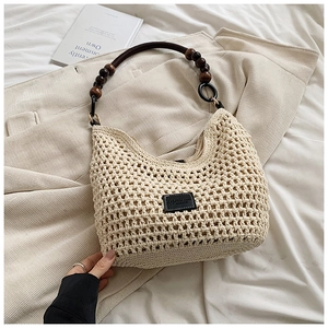 Detail of beige woven straw tote bag with vintage wood bead handles and leather patch