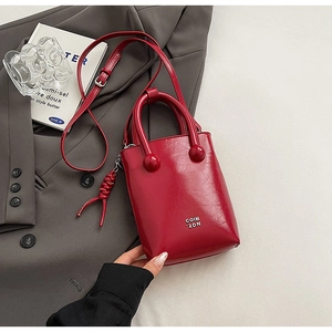 Vue détaillée d'un mini sac seau rouge montrant la texture du cuir et le logo en métal