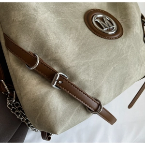Detail view of khaki canvas tote with brown leather trim and silver M-logo hardware