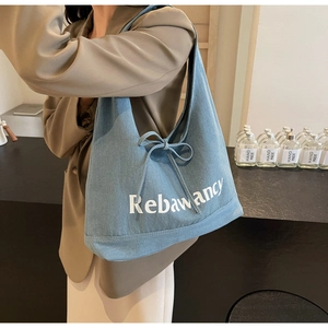 Detail of blue denim tote bag with Rebawancy print and decorative bow drawstring