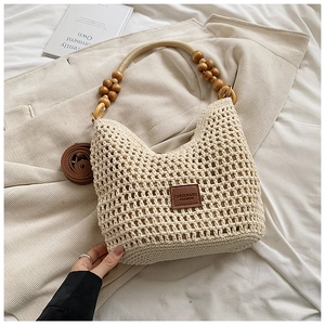 Detail of hand-woven crochet tote with round wooden bead handle and brown leather logo tag