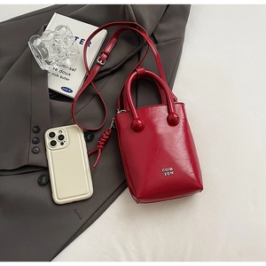 Vue détaillée d'un mini sac seau rouge avec poignées sphériques et logo de marque