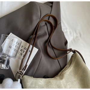 Close-up of light khaki canvas tote bag with brown leather strap and plush charm
