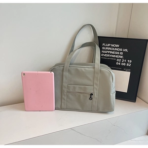 Gros plan d'un grand sac de voyage vert sauge avec une poche frontale zippée pratique