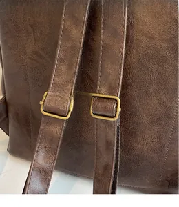 Detail of adjustable vintage gold buckles on dark brown faux leather backpack straps