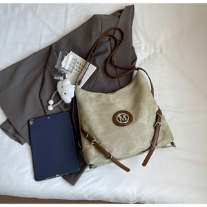 Flat lay of a large casual olive tote bag with leather straps and a white plush charm