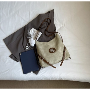Detail of green fabric hobo bag with M-logo, leather straps and plush cloud charm