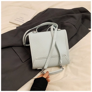 Detailaufnahme der hellblauen Handtasche mit V-Webstruktur und eleganten Metallbeschlägen