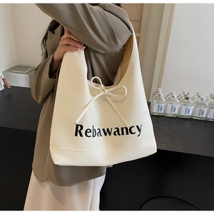 Detail of off-white canvas tote bag featuring bow ribbon decoration and chic printed letters