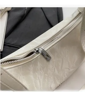 Detail of silver metal zipper closure on white pleated leather shoulder bag texture