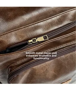 Detail of vintage brown leather backpack showing litchi texture and bronze metal zippers