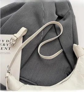 Close-up of cream crescent bag featuring cracked leather texture and silver buckle detail