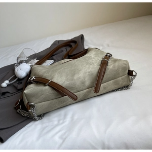Detail of vintage canvas tote bag with leather straps and metal chain on white bedding