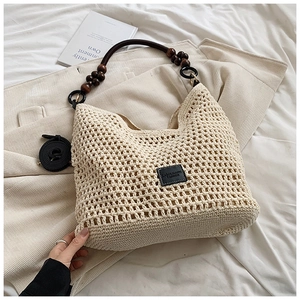 Detail of beige woven tote bag with wooden bead handle and black leather logo patch
