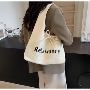 Detail of off-white canvas tote with Rebawancy print and side drawstring bow accent