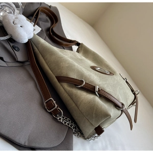 Detail of khaki canvas tote with brown leather straps and cloud charm accessory