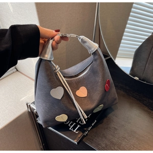 Detail of grey suede hobo bag with colorful 3D heart patches and silver metal ring handle