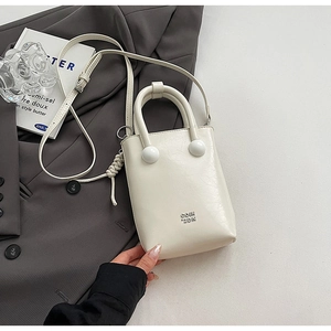 Détail du mini sac seau blanc crème avec boucles rondes et logo en métal poli
