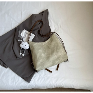 Detail of olive green vintage tote bag with plush cloud charm and brown leather strap