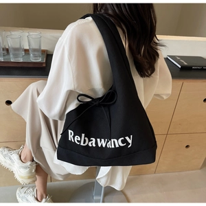Detail of a large black denim tote bag with Rebawancy text and a bow tie accent