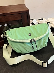 Mint green nylon crossbody saddle bag with wide shoulder strap in a cafe scene