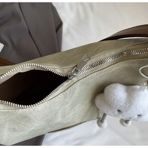 Detail of olive green canvas tote with silver zipper and a white cloud plush pendant