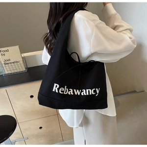 Detail view of large black denim tote bag with Rebawancy print and side drawstring bow