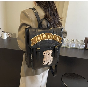 Detail of vintage black leather backpack featuring Holiday letter patch and bear embroidery