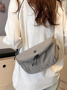 Casual khaki nylon crescent chest bag with adjustable strap worn by model in daily style
