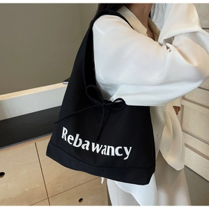 Detail of black canvas tote bag with Rebawancy lettering and side bow decoration