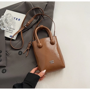 Détail d'un sac vintage en cuir ciré marron avec poignée ronde et ornement tissé