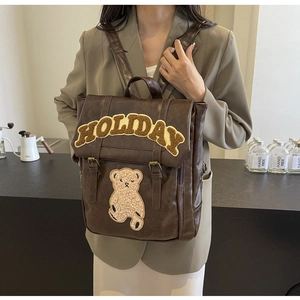 Detail of vintage brown faux leather backpack with holiday teddy bear embroidery