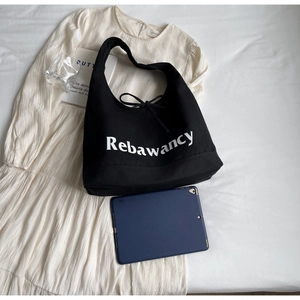 Detail view of large black canvas tote bag with white lettering and bow tie drawstring