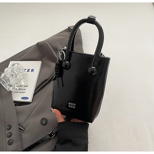 Détail du sac à main en cuir noir brillant avec le logo argenté COIN 2DN gravé