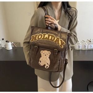 Brown leather backpack with HOLIDAY lettering and cute bear patch on a lifestyle model