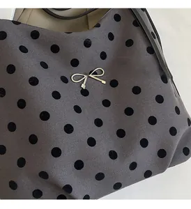 Détail du tissu à pois gris avec nœud en métal argenté sur un sac à bandoulière