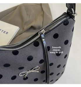 Gros plan sur la fermeture éclair en métal argenté du sac gris à pois noirs