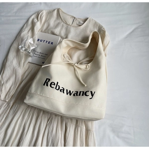 Detail of off-white canvas tote bag featuring Rebawancy text and decorative ribbon bow