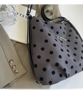 Détail du sac à bandoulière gris à pois avec un nœud en métal argenté et une sangle noire