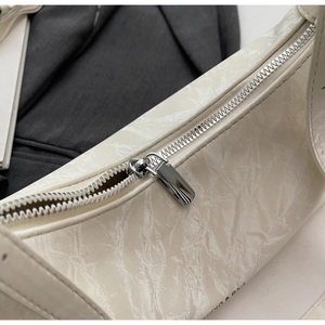 Macro shot of silver zipper and marbled texture on cream underarm bag for women