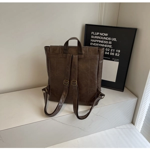 Back view of a vintage dark coffee backpack with matte leather texture and adjustable straps